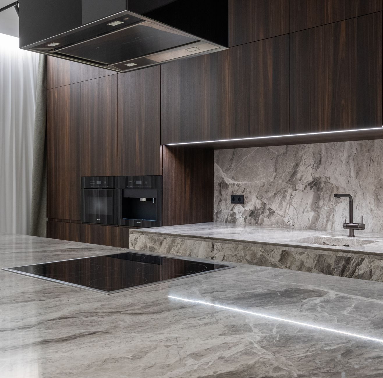 Close view of a natural stone countertop and backsplash against dark cabinetry